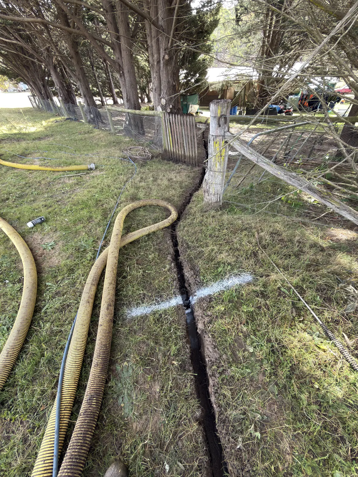 Vacuum and water hoses running along a trench